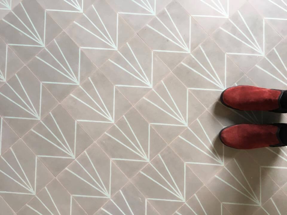 Suelo hidráulico colocado en una vivienda, con dibujo de abanico en verde claro sobre fondo color arena