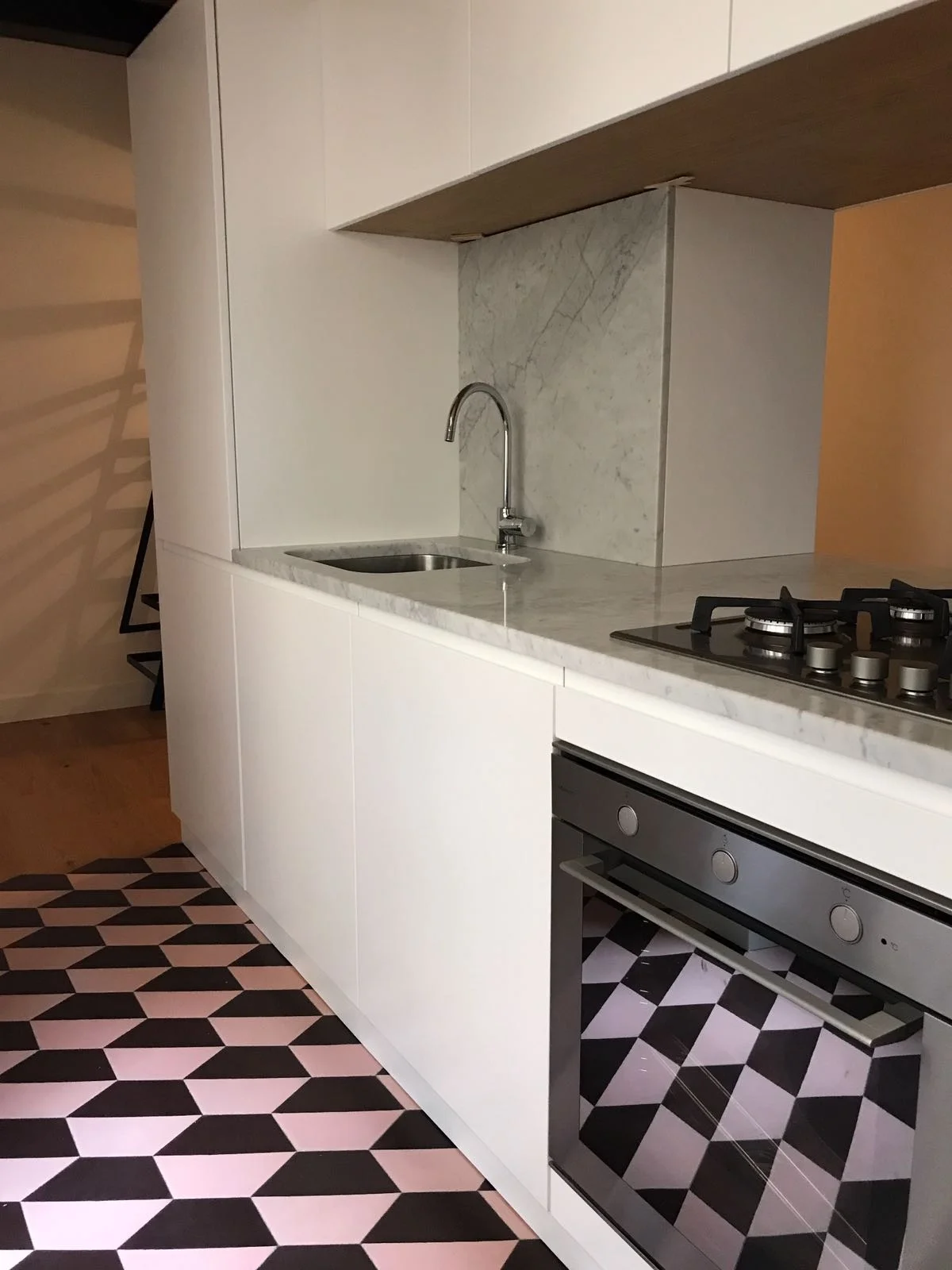 Cocina con suelo hidráulico de dibujo geométrico de cubos en negro, rosa y blanco