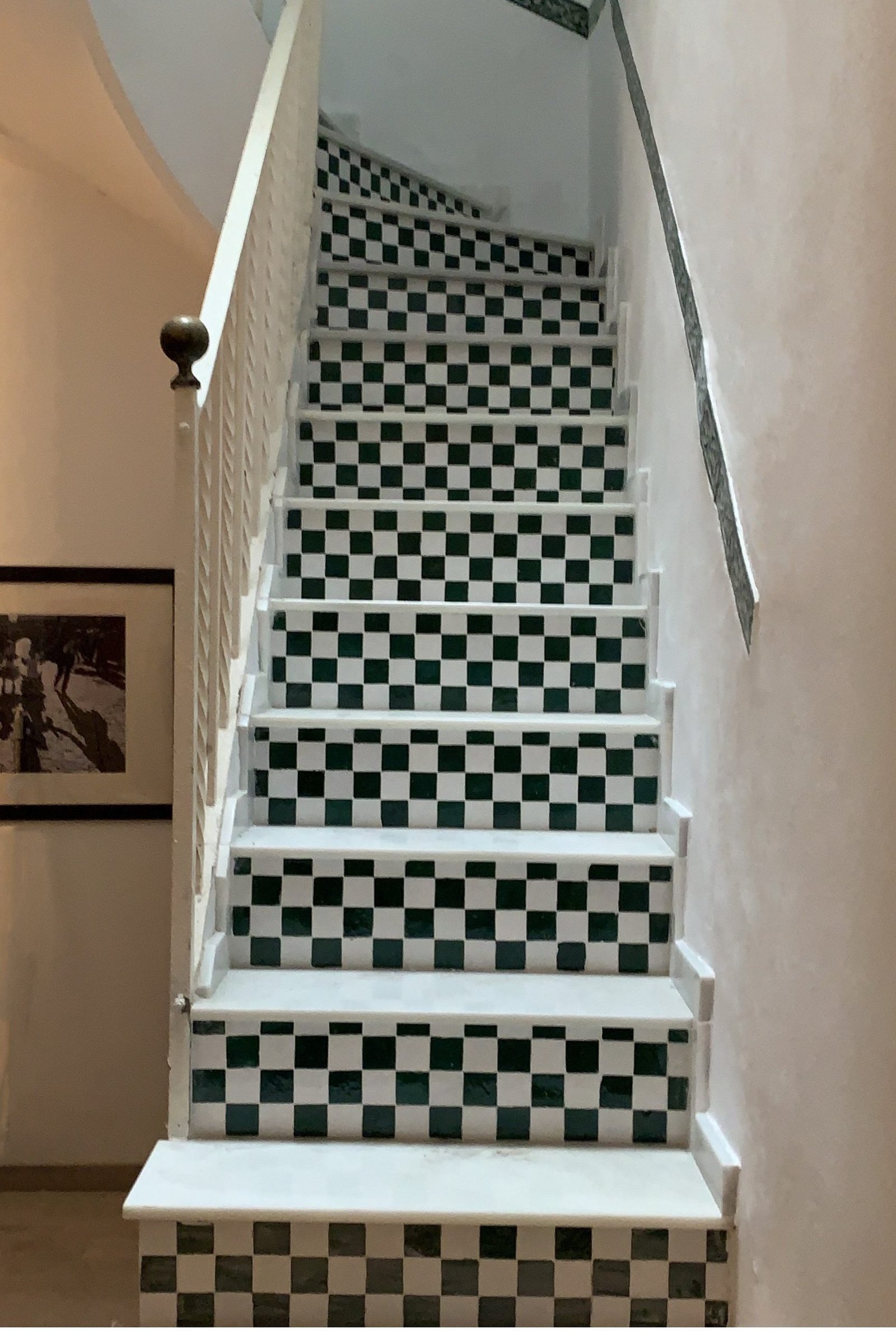 Escalera con damero de azulejo esmaltado verde y blanco en las contrahuellas y huellas de piedra clara